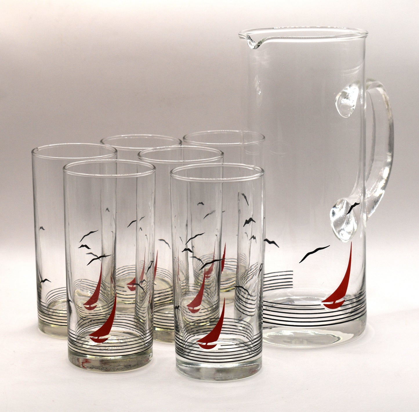 Glass pitcher and 6 matching tumblers with a nautical sailboat design.