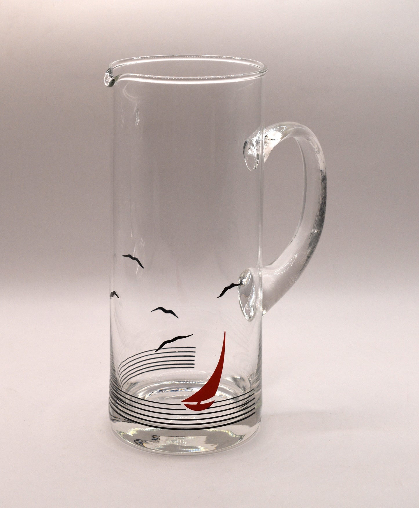 Glass pitcher and 6 matching tumblers with a nautical sailboat design.