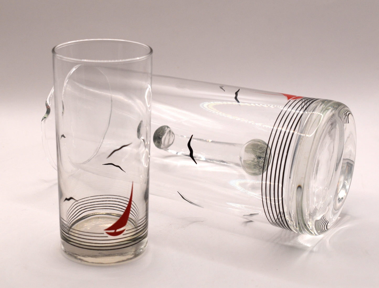 Glass pitcher and 6 matching tumblers with a nautical sailboat design.