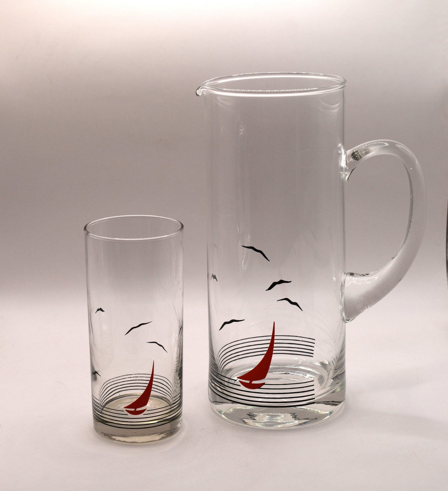 Glass pitcher and 6 matching tumblers with a nautical sailboat design.